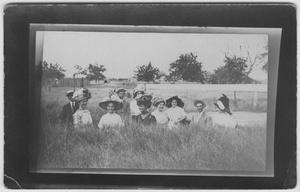 [Ten people sitting outdoors in the grass]