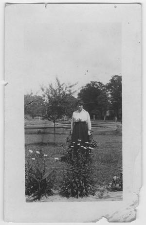 [A woman standing outdoors amongst flowers]