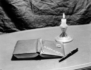 [Photograph of a diary and a lit candle]