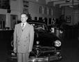 Photograph: [Photograph of a man posing in front of an automobile]