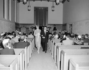 [A bride and groom walking down the church aisle]