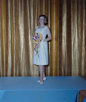 [Woman in formal attire posing in front of a curtain backdrop]