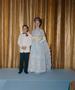 Primary view of [Boy and a woman in formal attire posing in front of a curtain backdrop]