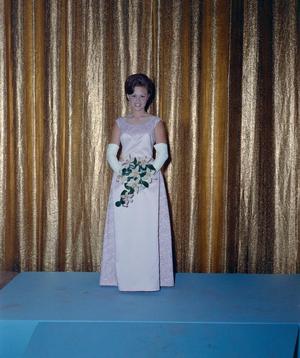 [Woman in formal attire posing in front of a curtain backdrop]