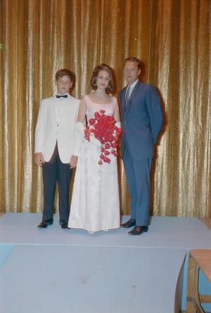 [Man, woman and boy in formal attire posing in front of a curtain backdrop]