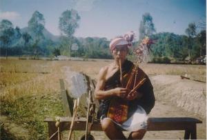 Photograph of a Kom man playing traditional instrument