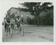 Photograph: [Female students on bicycles in front of West Hall]