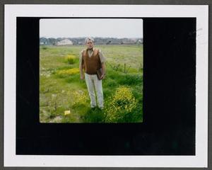 [Man standing in a field with houses in the background, 2]