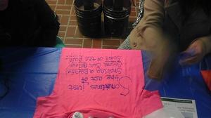 [Student decorating pink Clothesline Project t-shirt]