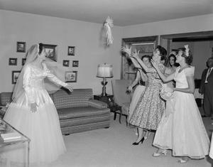 [A bride, Glenella Scarborough, tosses her bouquet to a group of women]