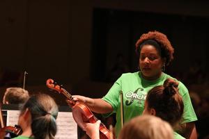 [Instructor teaching a student how to play a violin at the UNT Music Summer Orchestra Day Camp]