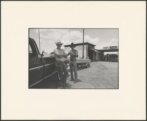 [Two men standing next to a truck]