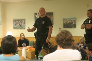 [Photograph of a police officer talking to UNT students in Traditions Hall]