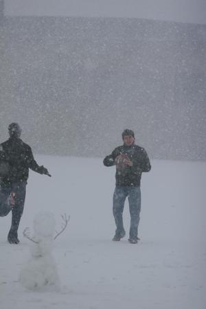 [Man holding a football in the snow]