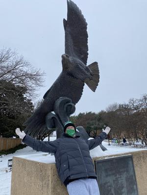 [Student and UNT Soaring Higher statue during winter storm]