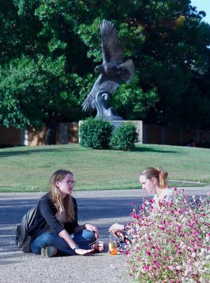 [Young women converse in front of eagle statue]