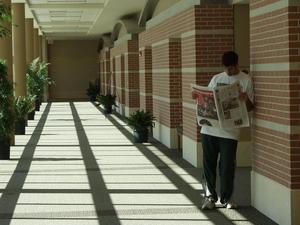 [Man reads newspaper in Gateway Center hallway]