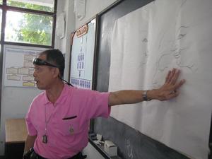 [Man in front of chalkboard at Thailand school]