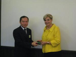 [Man 2 receives gift from Gretchen Bataille at NIDA delegation meeting]