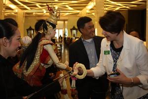 [Diane Crane receives garland from Thai puppet]