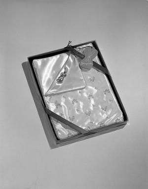 [Product photograph of a Schiaparelli gift box including a small perfume sample and folded satin garment]