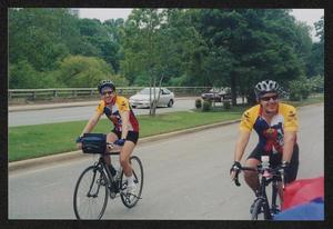 [Two cyclists riding side by side down a main road: Lone Star Ride 2003 event photo]