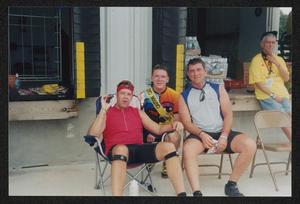 [Trio of cyclists sitting and snacking by loading docks: Lone Star Ride 2003 event photo]