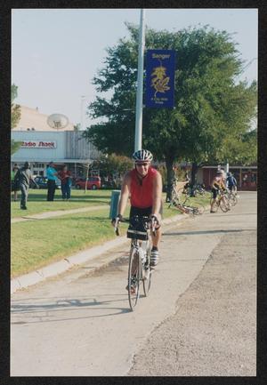 [Cyclist in a red vest riding into Sanger: Lone Star Ride 2003 event photo]