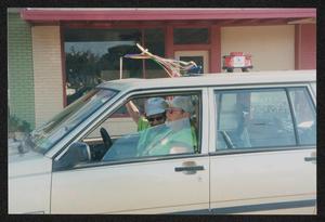 [Two crew members sitting in the front seat of a Volvo decorated with streamers: Lone Star Ride 2003 event photo]
