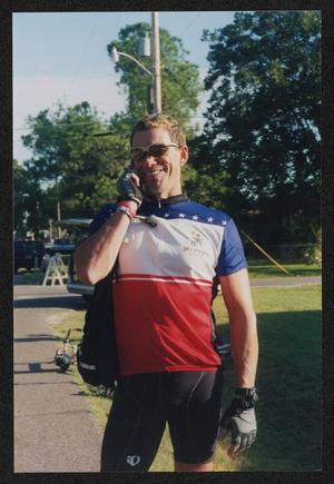 [Smiling cyclist talks on the phone: Lone Star Ride 2003 event photo]