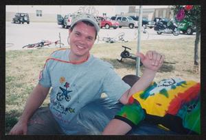 [Smiling volunteer with his elbow resting on a cyclists back: Lone Star Ride 2004 event photo]