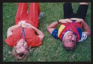 [Volunteer and a cyclist laying on the grass looking up at the camera: Lone Star Ride 2004 event photo]