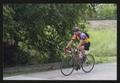 Primary view of [Smiling cyclist riding by a railroad track: Lone Star Ride event photo]