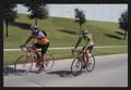 Photograph: [Two cyclists riding along a concrete road: Lone Star Ride event phot…