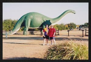 Primary view of object titled '[Two women posed in front of a large green dinosaur statue: Lone Star Ride 2005 event photo]'.