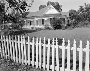 [The exterior of a house with a white picket fence]