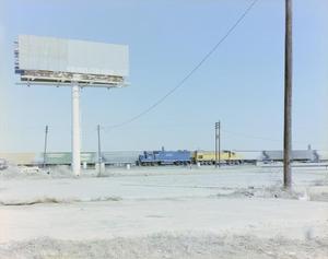 [Photograph of a large billboard with a passing train]