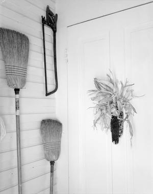 [Photograph of two brooms, saw, and corn]