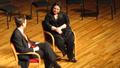 Photograph: [Heggie speaking with interviewer on stage, Student recital during Ja…