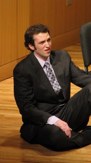 [Singer sitting on stage and performing at the Student recital during Jake Heggie's residency]