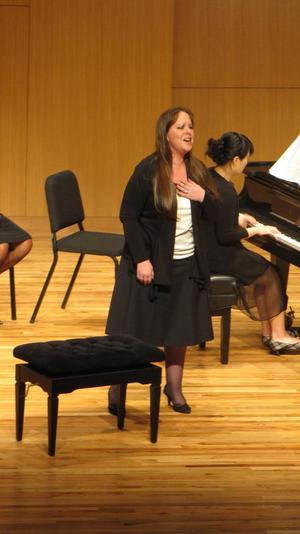 [Singer wearing a black and white outfit performing at the Student recital during Jake Heggie's residency]