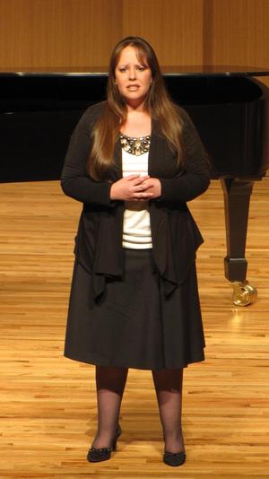 [Singer wearing a black and white outfit performing at the Student recital during Jake Heggie's residency]