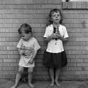 [Two children standing in front of a brick wall #6]