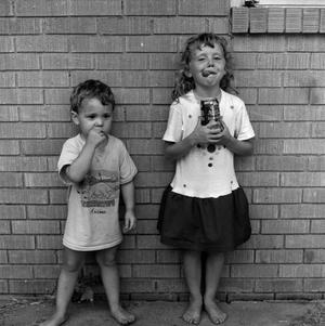 [Two children standing in front of a brick wall #7]