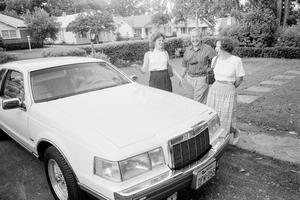 [Three individuals standing next to an automobile, 2]