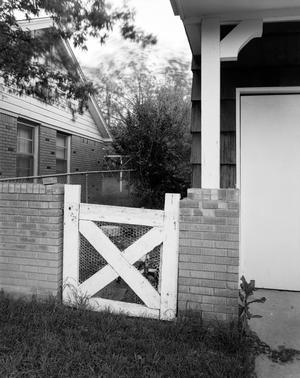 [A gate to a yard, next to a house]