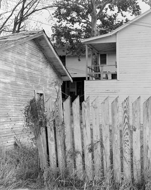 [A wooden fence and two old houses]