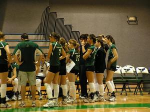 [UNT volleyball team huddles on the sidelines]