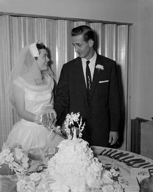 [Bride and groom Lajean Valentine Hitch and James Alan Wharton cutting into their cake]