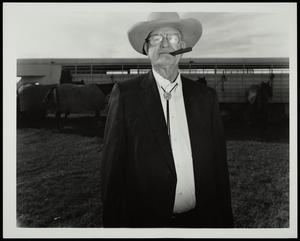 [An unknown man at a polo match, wearing a suit]